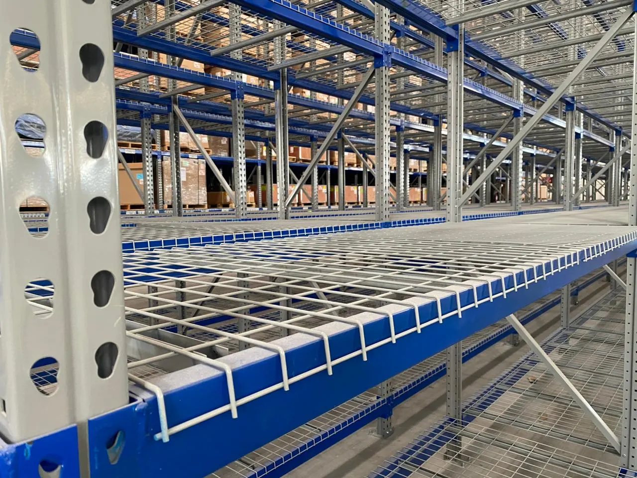 Parrillas metálicas instaladas en un rack selectivo azul con vigas y marcos