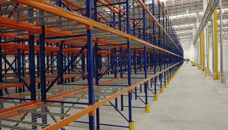 Rack selectivo de RC Racks instalado en un almacén, marcos azules y vigas naranjas